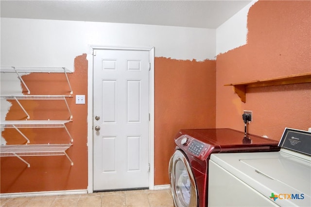 clothes washing area featuring washer and dryer and light tile patterned floors