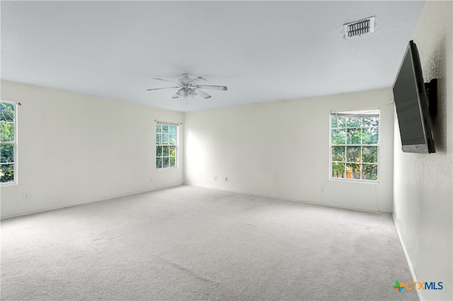 carpeted empty room featuring ceiling fan and a healthy amount of sunlight