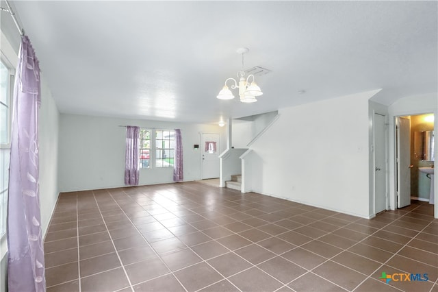 unfurnished living room with dark tile patterned flooring and a chandelier