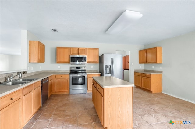 kitchen with appliances with stainless steel finishes, sink, a center island, and light tile patterned floors