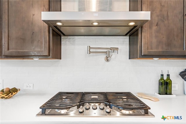 kitchen with dark brown cabinetry, stainless steel gas stovetop, extractor fan, and light countertops