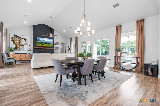 dining room with light wood-type flooring, high vaulted ceiling, visible vents, and ceiling fan with notable chandelier