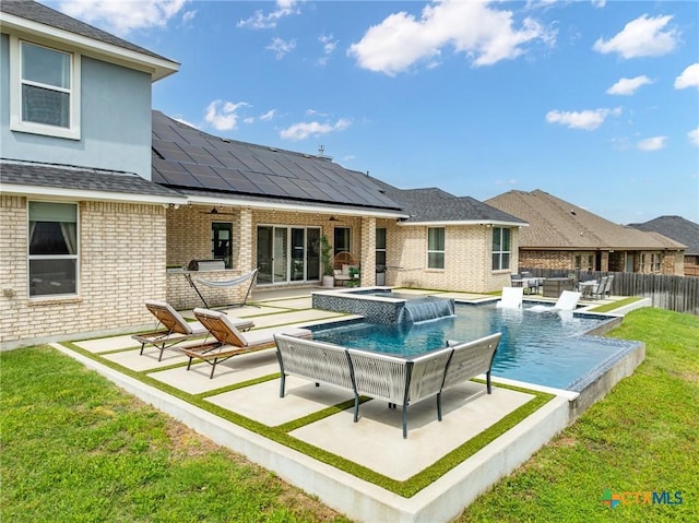 back of property featuring ceiling fan, an in ground hot tub, brick siding, fence, and a yard