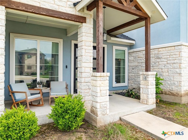 property entrance with a porch, stone siding, and stucco siding