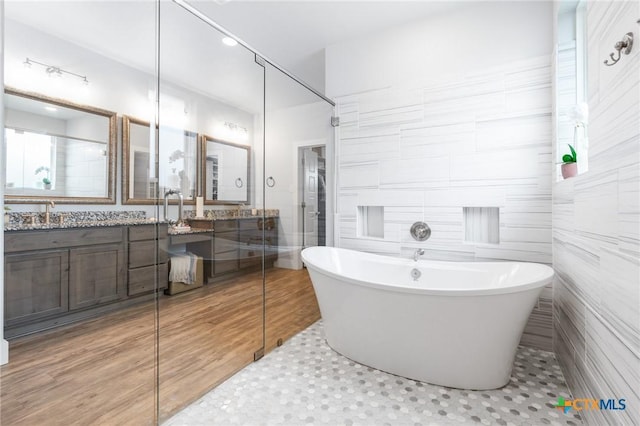 bathroom featuring a soaking tub, a shower, tile walls, and vanity