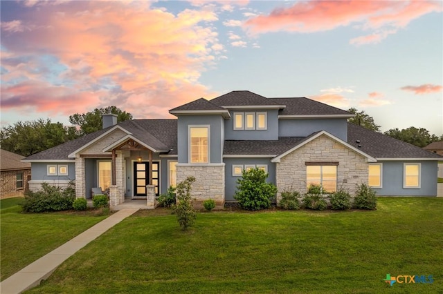 view of front of house featuring stone siding, a chimney, a lawn, and stucco siding