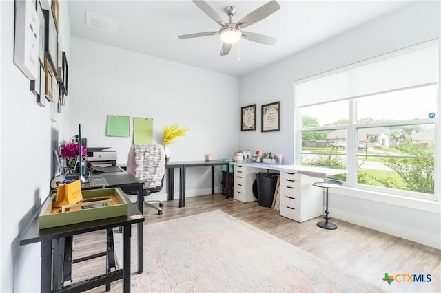 office space with light wood-type flooring, ceiling fan, visible vents, and baseboards