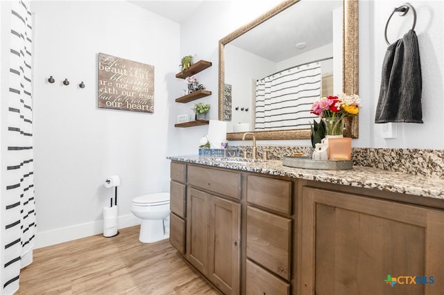 bathroom featuring curtained shower, toilet, vanity, wood finished floors, and baseboards