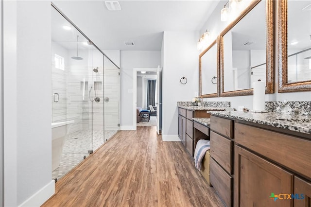 bathroom featuring wood finished floors, visible vents, vanity, baseboards, and a stall shower