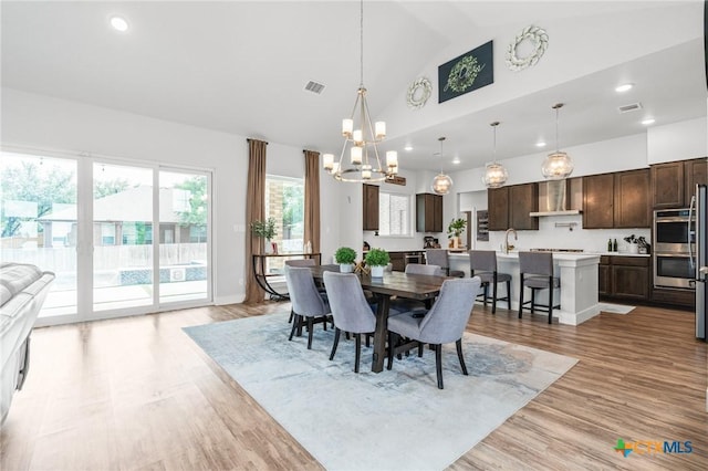 dining room with high vaulted ceiling, a notable chandelier, recessed lighting, visible vents, and light wood-style floors