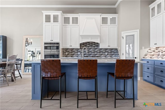1745 Alta Vista Loop, Temple, TX 76502 - kitchen with light countertops, white cabinets, ornamental molding, an island with sink, and double oven