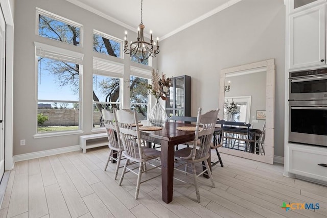 1745 Alta Vista Loop, Temple, TX 76502 - dining space with crown molding, light wood finished floors, baseboards, a high ceiling, and an inviting chandelier