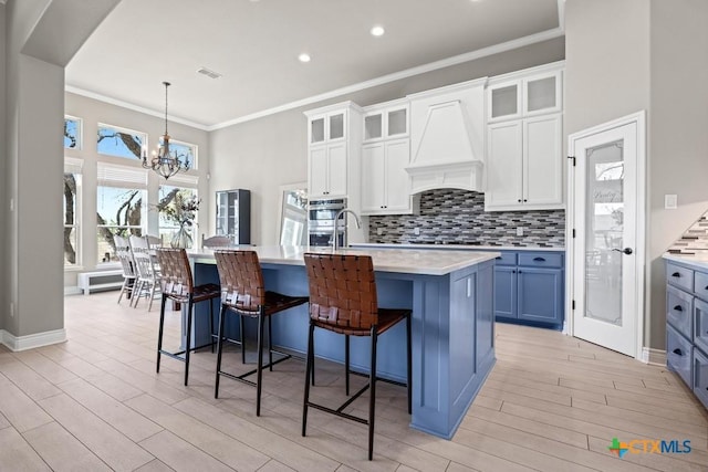 1745 Alta Vista Loop, Temple, TX 76502 - kitchen featuring light countertops, light wood-style flooring, a chandelier, premium range hood, and backsplash