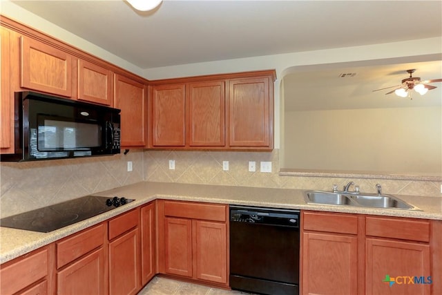 kitchen with tasteful backsplash, brown cabinets, light countertops, black appliances, and a sink