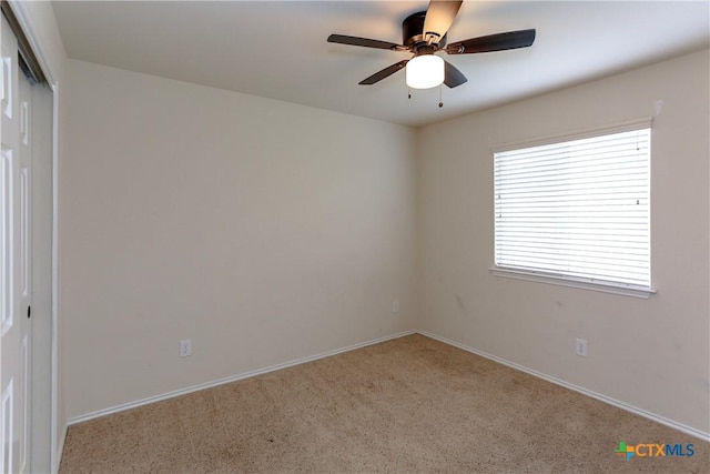 carpeted empty room with ceiling fan and baseboards