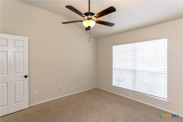 empty room featuring lofted ceiling, ceiling fan, baseboards, and light colored carpet