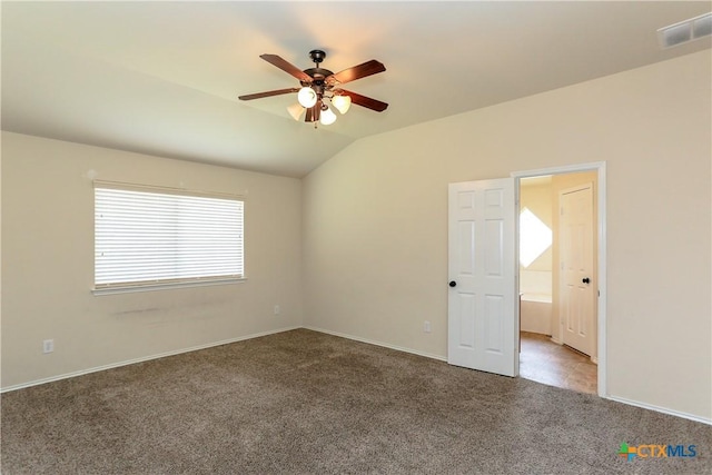 spare room with carpet floors, lofted ceiling, visible vents, a ceiling fan, and baseboards