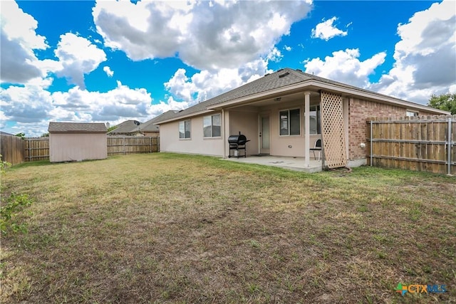 back of property featuring an outbuilding, a fenced backyard, a yard, a shed, and a patio area