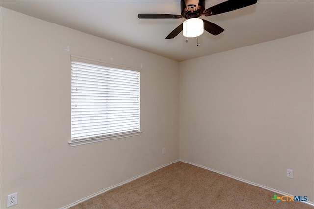 carpeted spare room featuring ceiling fan and baseboards