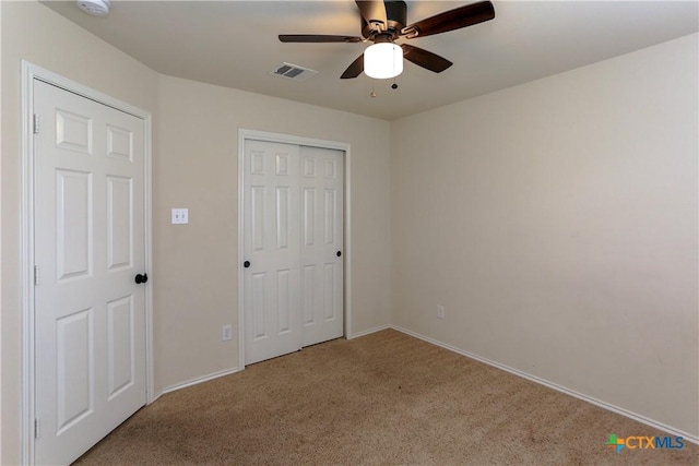 unfurnished bedroom featuring carpet floors, a closet, visible vents, a ceiling fan, and baseboards