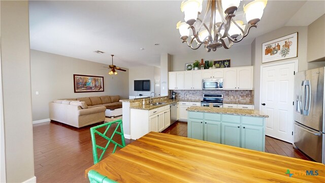 101 Arabian Dr, Victoria, TX 77904 - kitchen featuring appliances with stainless steel finishes, tasteful backsplash, dark wood finished floors, white cabinets, and a chandelier