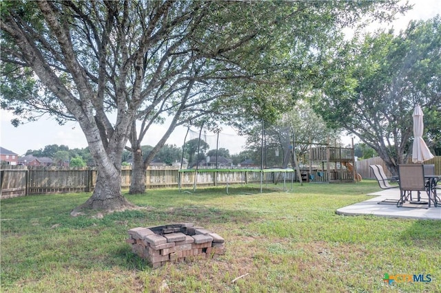 101 Arabian Dr, Victoria, TX 77904 - fenced backyard with a trampoline, a patio area, an outdoor fire pit, and a playground