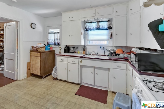 kitchen featuring sink, white range, white cabinets, tile counters, and decorative backsplash