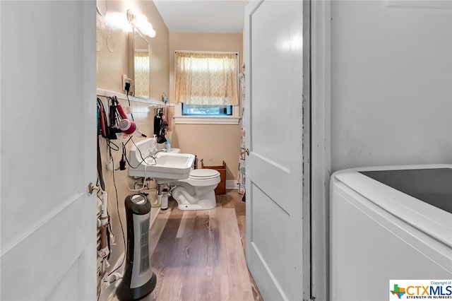 bathroom with toilet, washer / clothes dryer, sink, and wood-type flooring