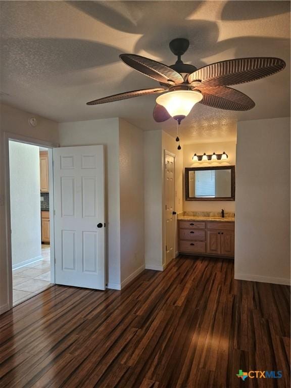 unfurnished bedroom with baseboards, ensuite bathroom, ceiling fan, and dark wood-style floors