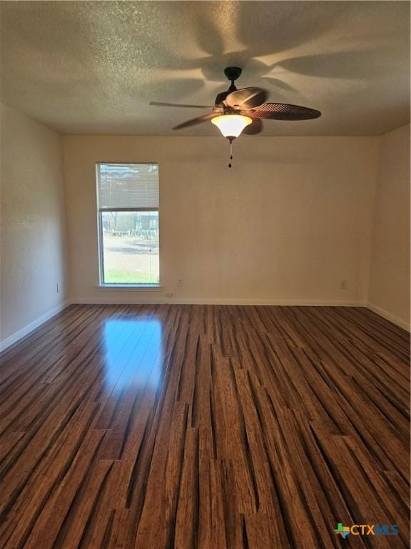 empty room with dark wood finished floors, baseboards, a ceiling fan, and a textured ceiling