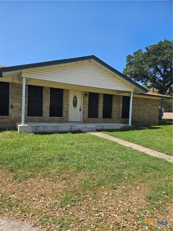 view of front facade with a porch, a front lawn, and stone siding