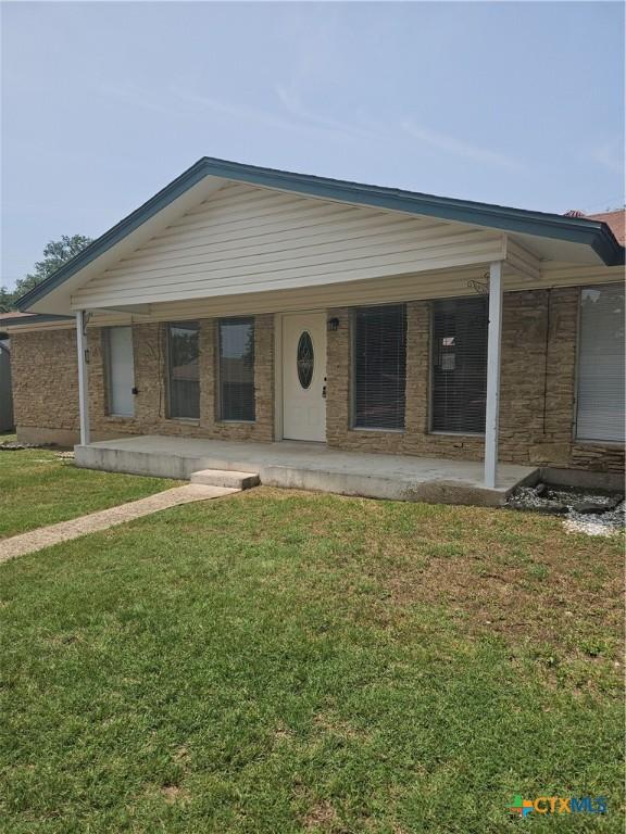 view of front of house featuring a front yard, covered porch, and brick siding