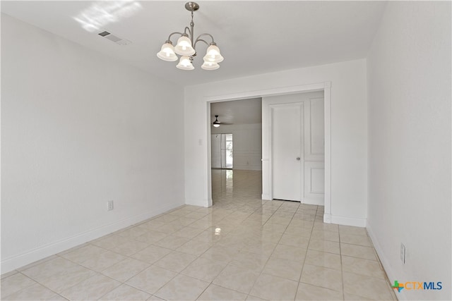 empty room with a chandelier and light tile patterned floors