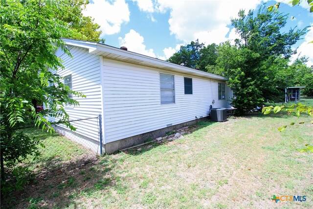 view of property exterior with central AC and a yard