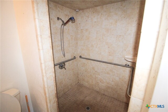 bathroom featuring toilet and a tile shower