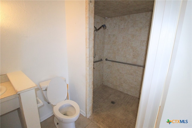 bathroom featuring toilet, vanity, tile patterned flooring, and tiled shower