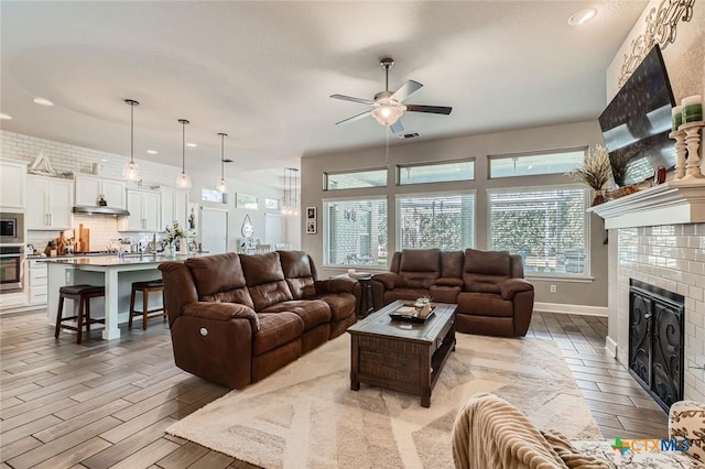 living room with wood tiled floor, recessed lighting, a ceiling fan, and a tile fireplace