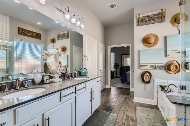 bathroom featuring a sink, visible vents, wood finish floors, and double vanity