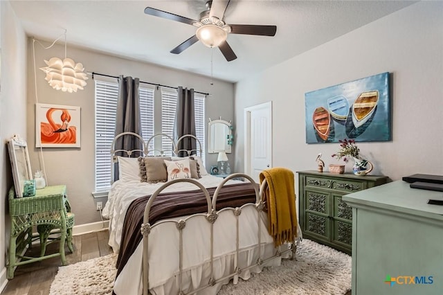 bedroom featuring baseboards, wood finished floors, and a ceiling fan