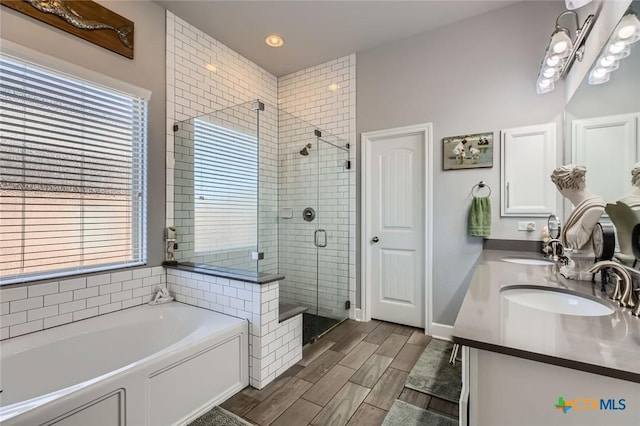 bathroom with a garden tub, a shower stall, wood finish floors, and a sink