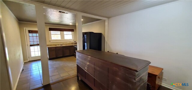 interior space with tile patterned flooring, sink, ensuite bathroom, crown molding, and black refrigerator