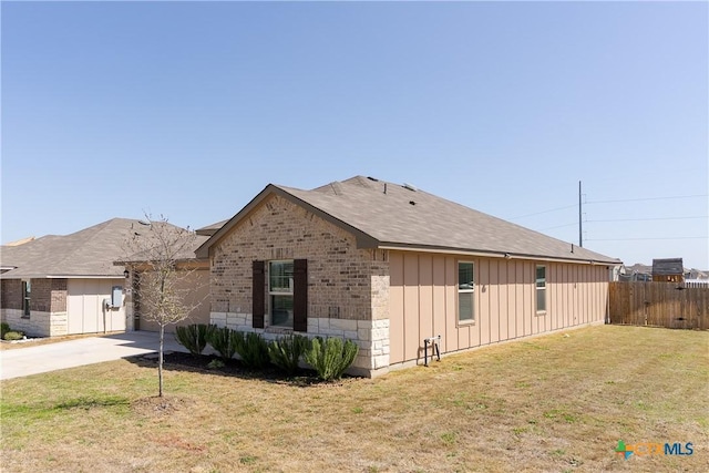 view of front of property featuring a front yard, fence, driveway, brick siding, and board and batten siding