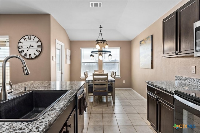 kitchen featuring visible vents, a sink, an inviting chandelier, light tile patterned floors, and vaulted ceiling