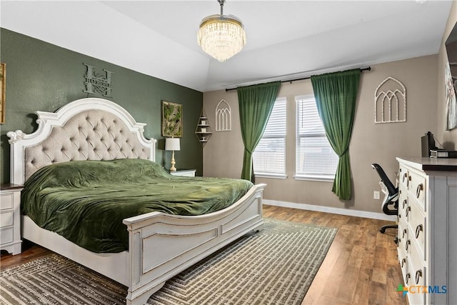 bedroom featuring a chandelier, baseboards, and wood finished floors