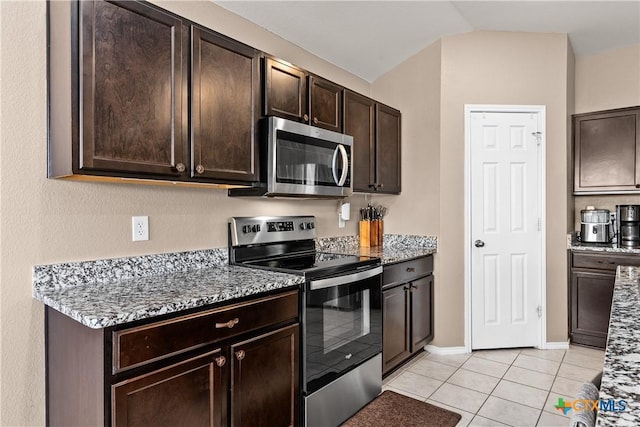 kitchen with light tile patterned floors, light stone countertops, dark brown cabinetry, and appliances with stainless steel finishes