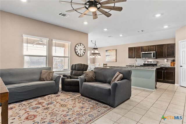 living area with light tile patterned floors, a ceiling fan, and visible vents