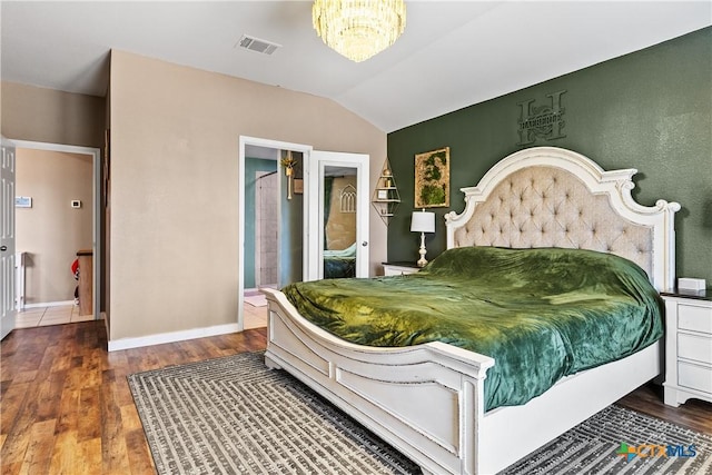 bedroom featuring visible vents, baseboards, a chandelier, lofted ceiling, and wood finished floors