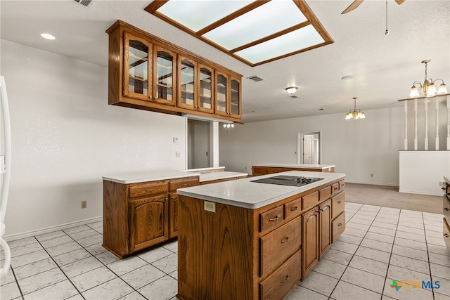 kitchen featuring light tile patterned floors, ceiling fan with notable chandelier, a center island, black electric stovetop, and decorative light fixtures