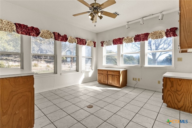 unfurnished sunroom featuring rail lighting and ceiling fan