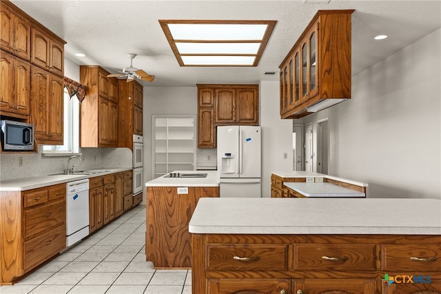 kitchen with light tile patterned flooring, tasteful backsplash, sink, a center island, and white appliances